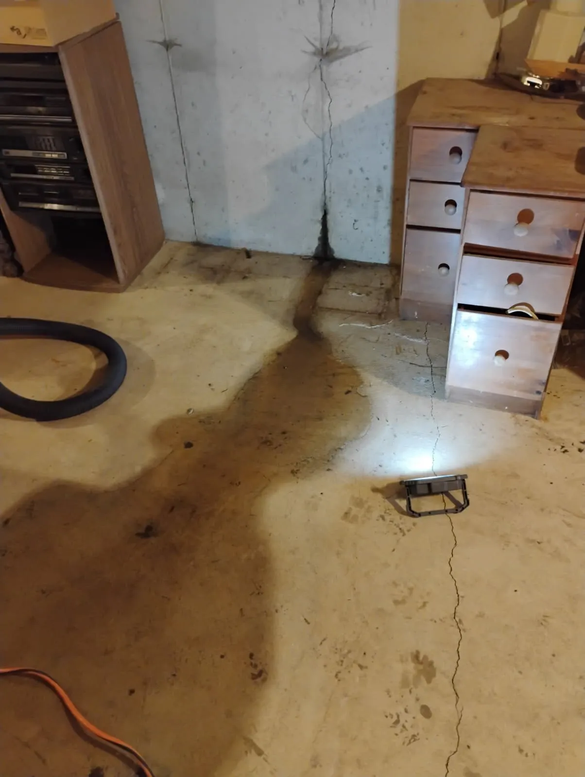 Active water leak streaming through foundation crack in Framingham basement