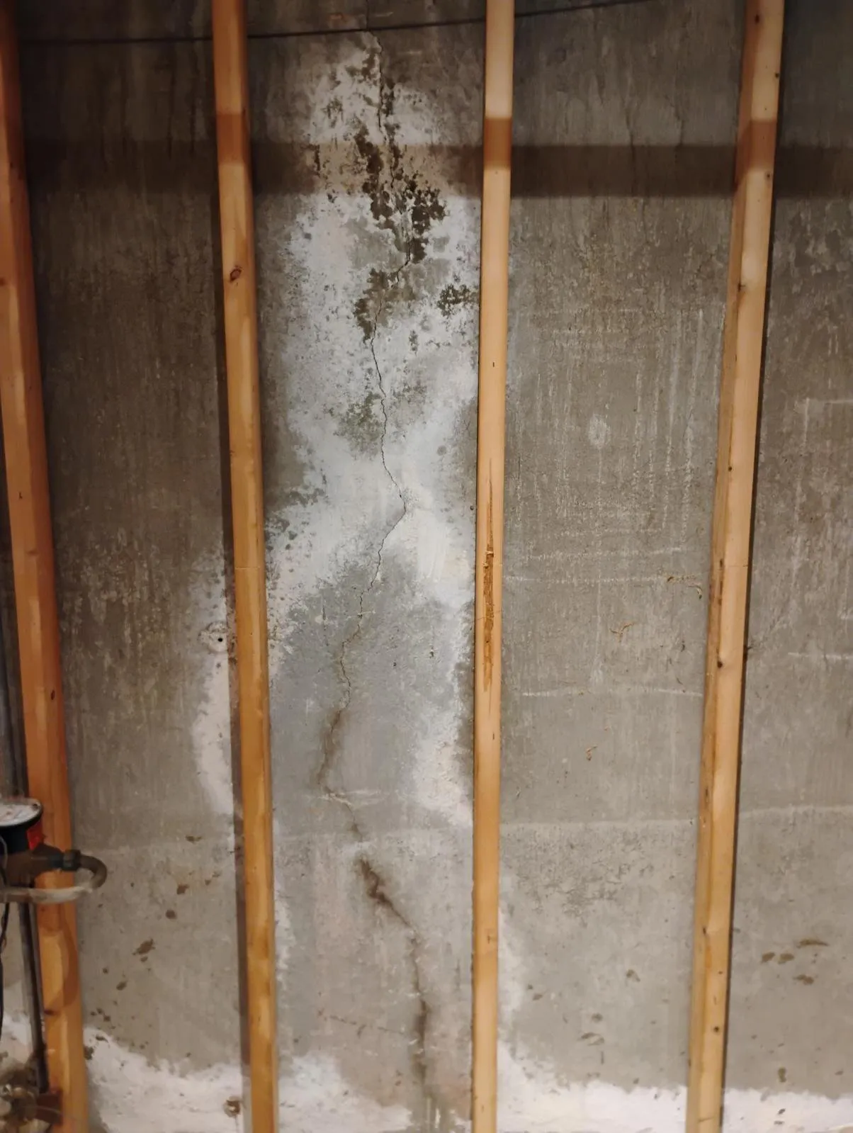 Foundation settling crack behind wall paneling in flooded Shrewsbury basement