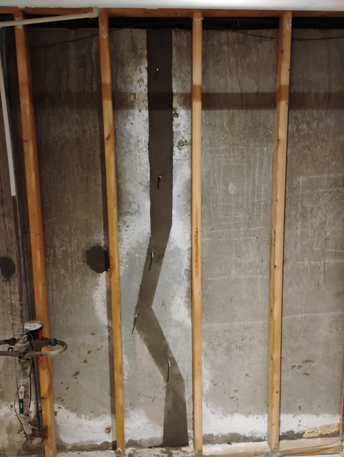 Foundation crack exposed behind removed wall paneling in Shrewsbury basement