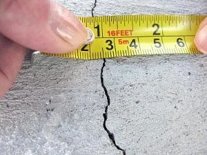 Vertical foundation crack in concrete basement wall showing typical settling pattern