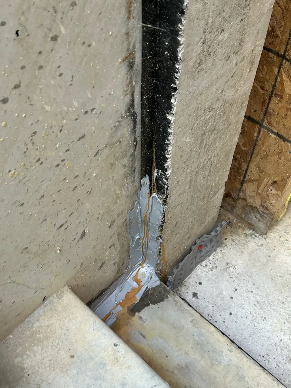 Failed bulkhead sealant with rust staining at concrete joint